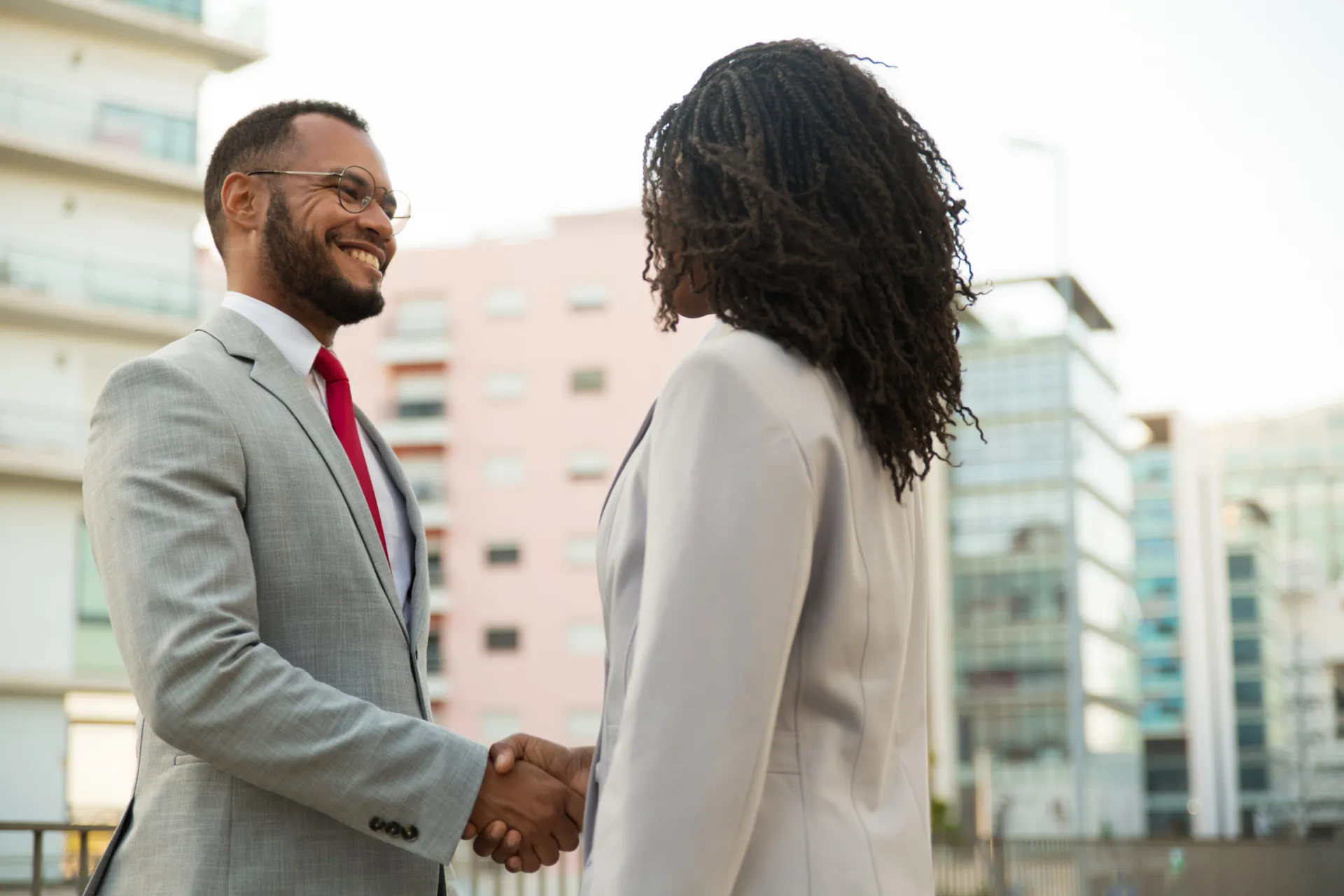 Two business professionals shaking hands outside an office building